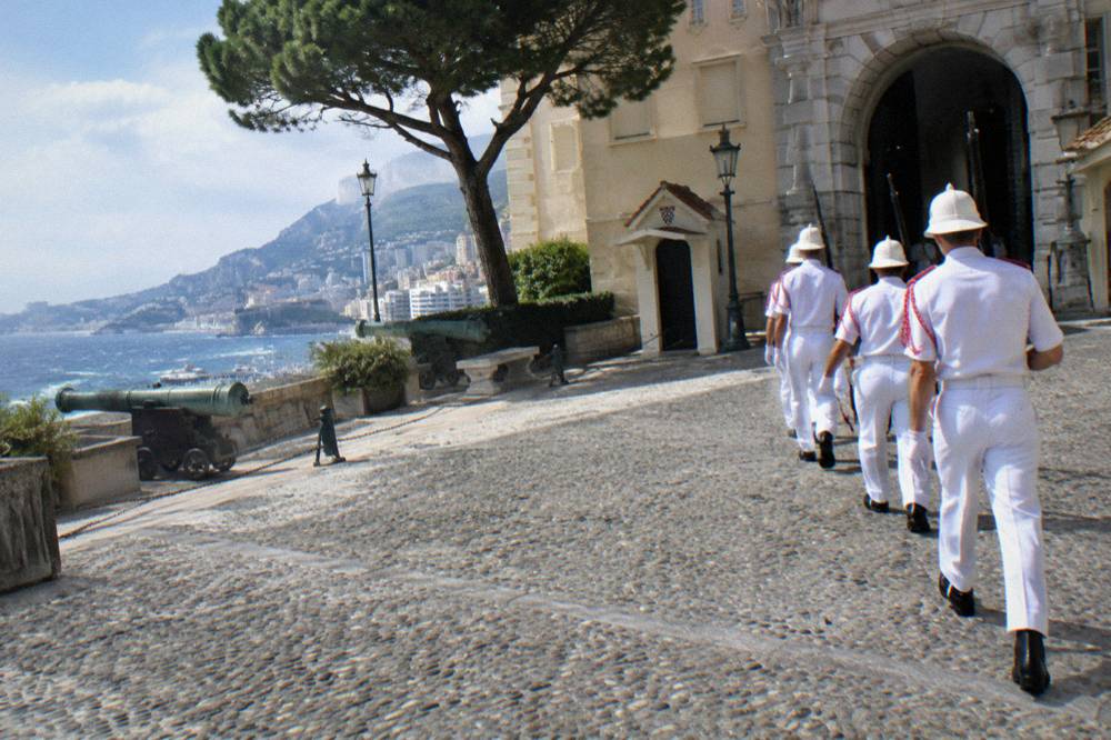 Palace guards in uniform marching across the cobblestone courtyard during the midday ceremony