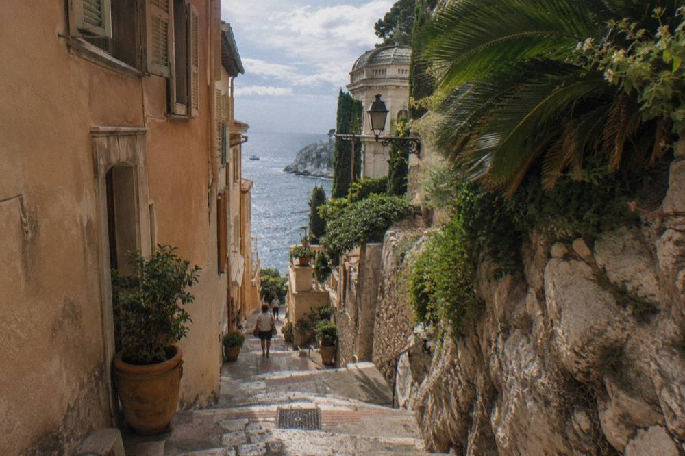 Narrow stone street on the Rock of Monaco with old buildings and a glimpse of the sea