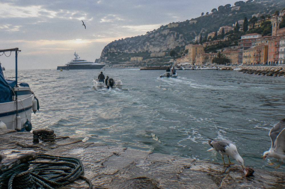 Tender boats crossing the calm bay of Villefranche-sur-Mer toward a cruise ship at anchor