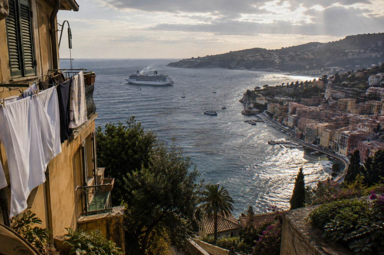 Cruise ship anchored in the bay of Villefranche-sur-Mer with pastel waterfront buildings along the shore