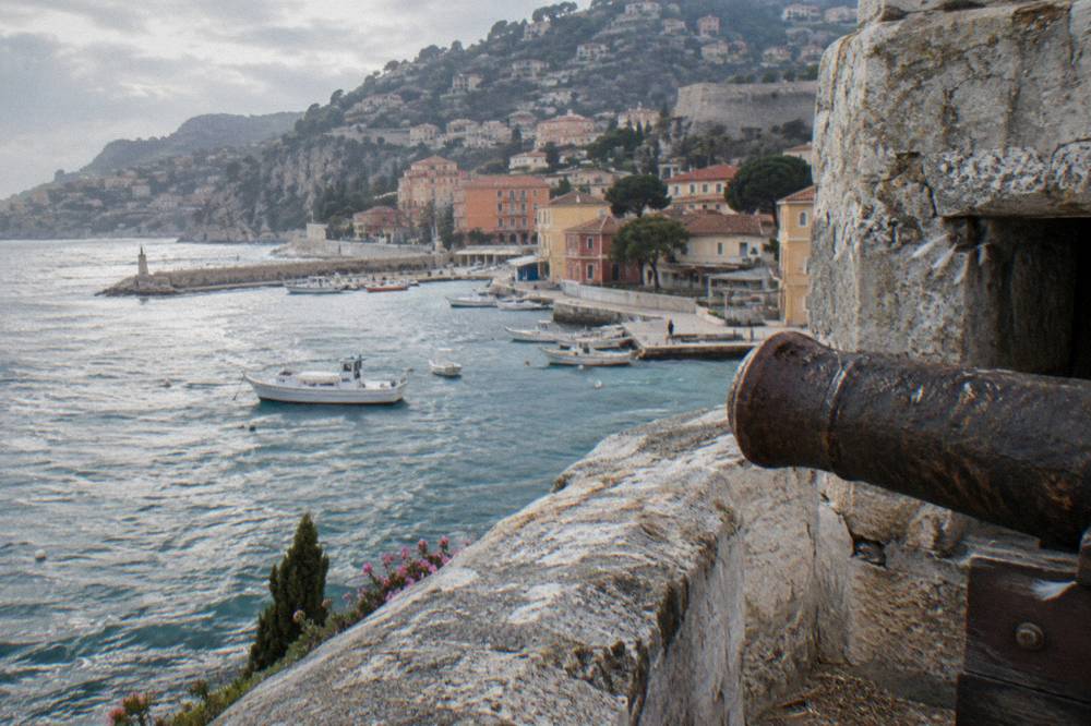 A stone fortress wall above a Mediterranean harbour with boats