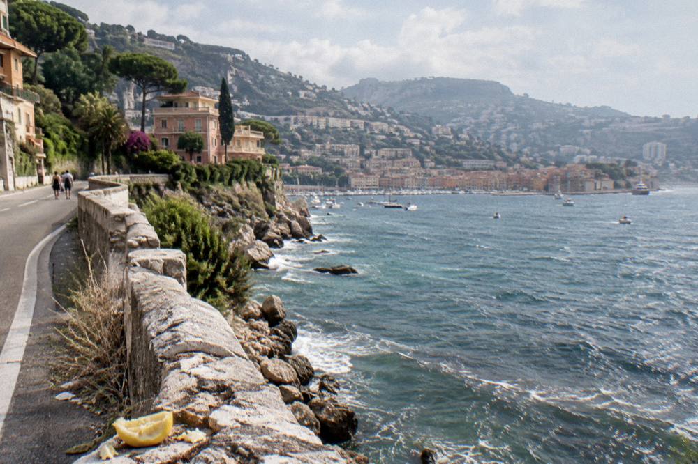 A winding corniche road above cliffs with a village in the distance