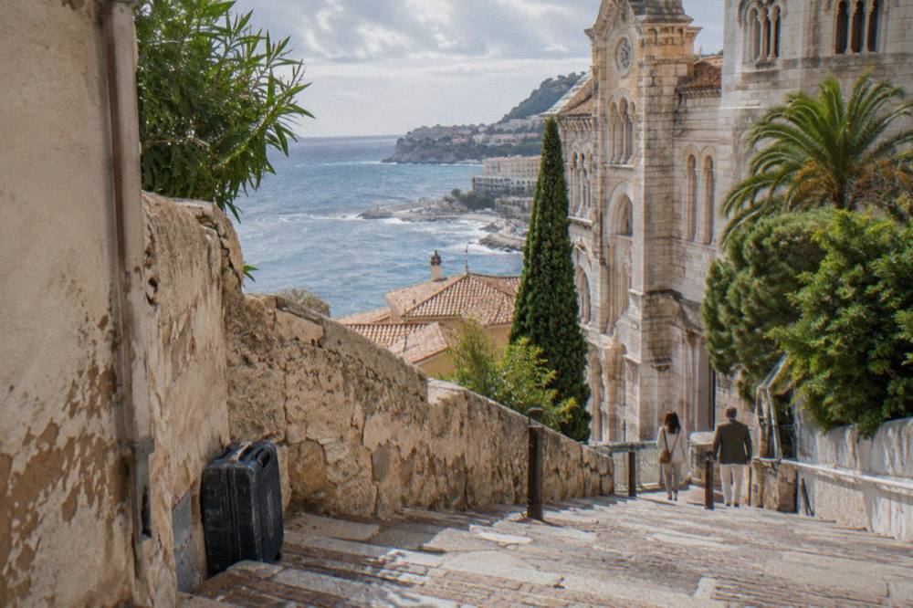 Smart casual visitors walking a sunlit stone lane in Monaco old town
