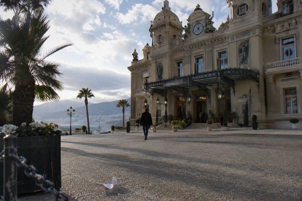 Visitor in neat jeans and a jacket outside the ornate Casino de Monte-Carlo facade