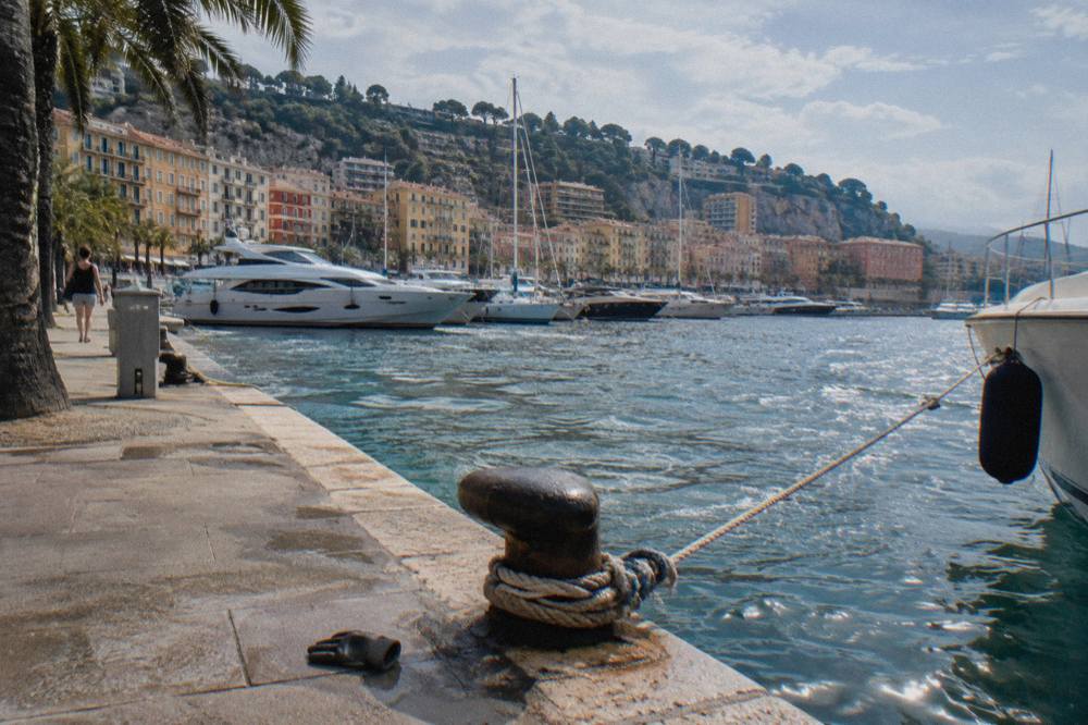 Pastel buildings along the Nice waterfront with palm trees and a wide seaside promenade