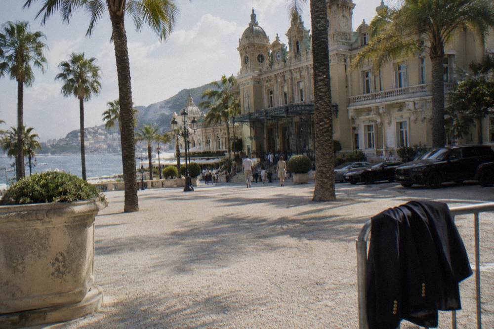 Luxury hotel facade and palm-lined square in Monte Carlo with luxury cars parked outside