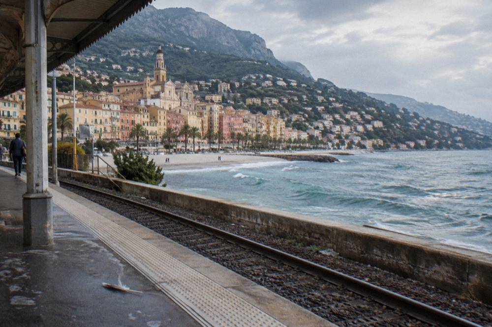 Colorful facades of Menton old town rising above a small beach with calm sea