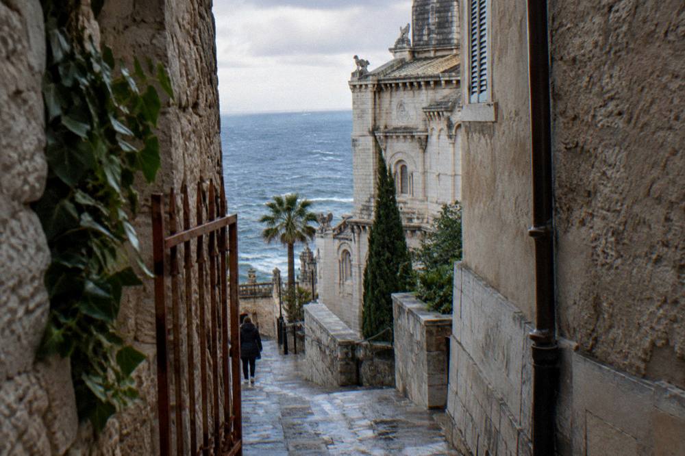 Old town alley on the Rock of Monaco with stone walls and sea glimpses between buildings