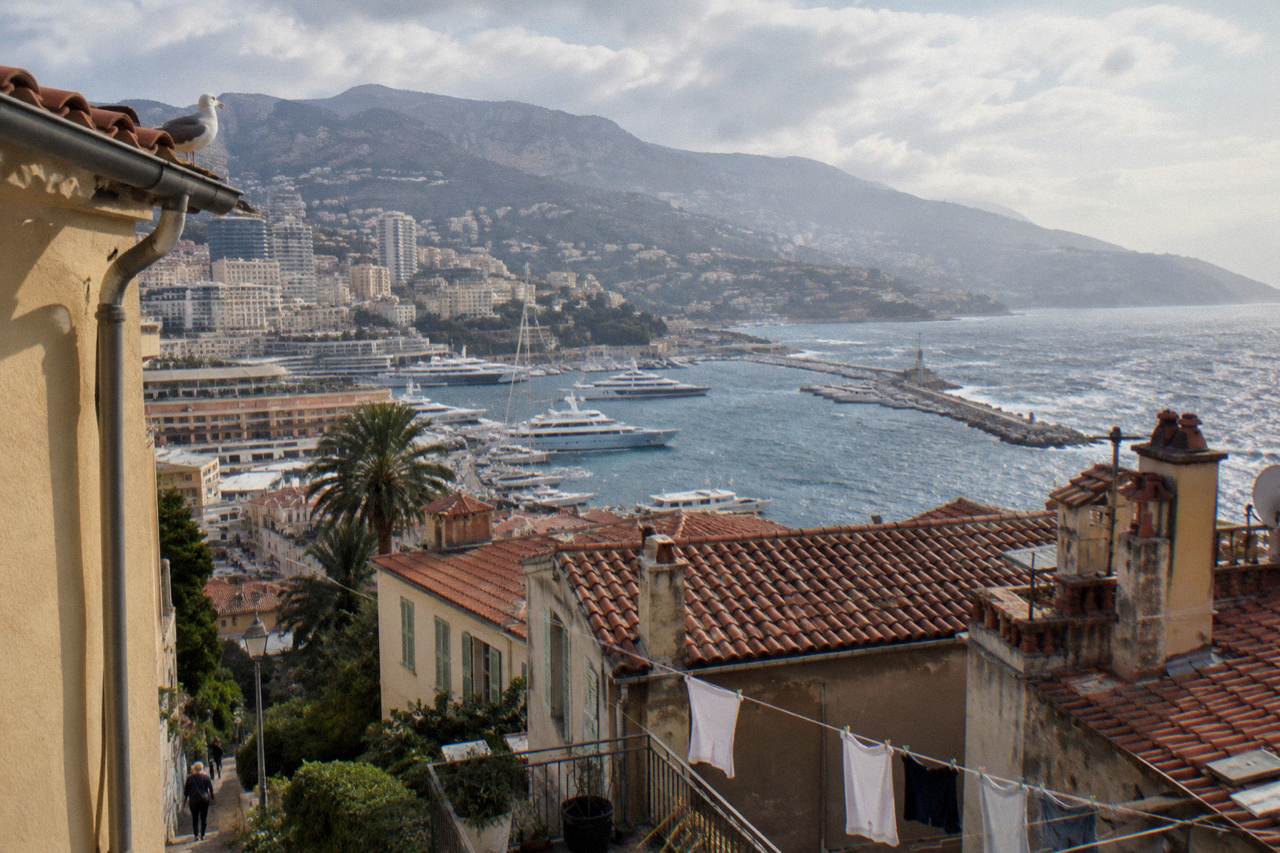 View over red rooftops of Nice with the Mediterranean coastline curving toward hills in morning light